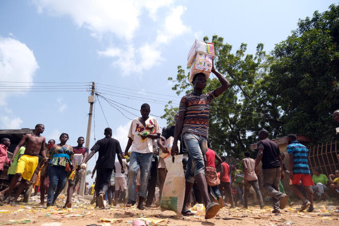 Des gens emportent des sacs de nourriture après le pillage d’un entrepôt d’aide alimentaire, à Abuja, au Nigeria, le 26 octobre 2020. Les vivres stockées étaient destinées à soulager la faim pendant le confinement mais n’ont jamais été distribuées.