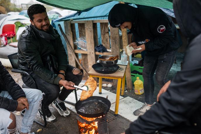 Un groupe de jeunes Afghans se retrouvent pour faire cuire du pain (« bolani ») sur un brasero de fortune à l’intérieur du campement en bordure de canal, le 2 novembre, à Saint-Denis (Seine-Saint-Denis).