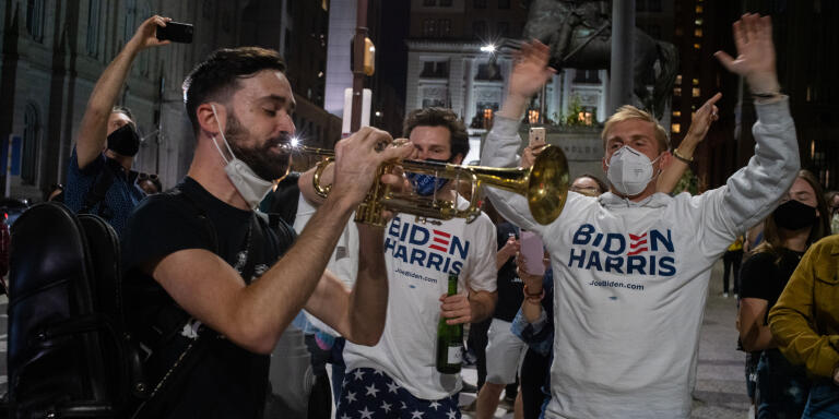 Un supporteur de Biden joue l'hymne national des Etats-Unis à la trompette. Les résidents de Philadelphie célèbrent la victoire de Joe Biden devant la mairie de Philadelphie. 7 novembre 2020. Philadelphie, Pennsylvanie. ©Benjamin Petit pour Le Monde