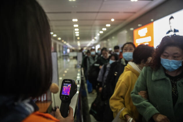 Une employée de la gare de Guiyang prend la température des passagers à leur arrivée, le 20 octobre.