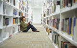Young woman sitting on library floor