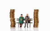 Figurines of old age pensioner sitting on bench between coin stacks