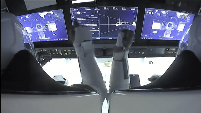 Dans cette capture d’écran de NASA TV, les astronautes Mike Hopkins (à gauche) et Victor Glover surveillent les commandes à bord de SpaceX Dragon.