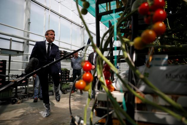Emmanuel Macron, couvre-chaussures de protection aux pieds, s’entretient avec des agriculteurs et des travailleurs d’une serre pour tomates alors qu’il visite la ferme de Jean-Marc Roué, à Cléder (Finistère), le 22 avril.