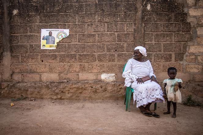 Une femme est assise à côté de l’affiche de campagne du président sortant Roch Marc Christian Kaboré, à Ouagadougou, le 6 novembre.