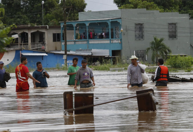 Des habitants dans une rue submergée de la ville de La Lima, au Honduras, le 18 novembre.