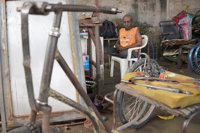 François, handicapé depuis l’âge de 5 ans, attend que les ouvriers réparent son tricycle dans l’atelier de Mafiki Mboyo, à Kinshasa, en novembre 2020.