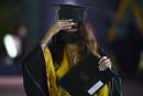 A graduate of Bahrain Bayan School wearing a face mask receives her diplomas at Bahrain International Circuit (BIC) in Sakhir race track on June 10, 2020 south of Bahraini capital Manama. - Eighty-two high school graduates received their diplomas in a special ceremony that observed social distancing regulations to minimise risk of exposure to the Covid-19 coronavirus. Graduates and their families remained in their cars before each student, wearing a face mask and being disinfected, walked from the car to the stage to receive the diploma. (Photo by Mazen Mahdi / AFP)