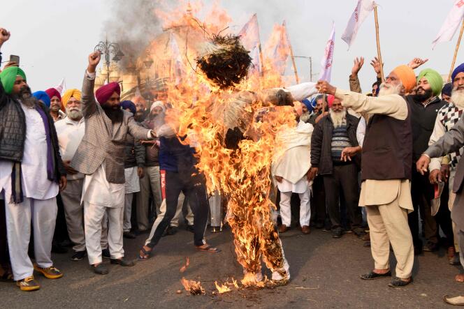 Les agriculteurs brûlent, à Amritsar (Inde), le 5 décembre, une effigie du premier ministre indien Narendra Modi, du président de la société Reliance Industries, Mukesh Ambani, et du président et fondateur du groupe Adani, Gautam Adani.