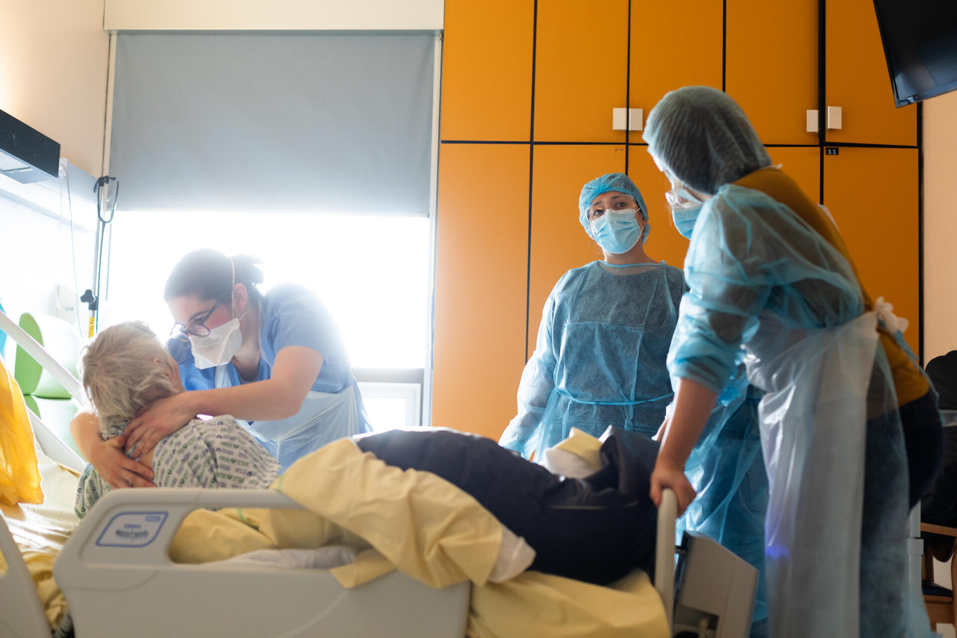 Une kinésithérapeute mobilise une patiente atteinte du Covid-19 sous le regard des médecins, au service de gériatrie de l’hôpital Bichat à Paris, le 8 décembre.