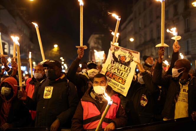 Des manifestants brandissent des bougies et des pancartes lors d’une manifestation pour la régularisation des sans-papiers, à l’occasion de la Journée internationale des migrants, le 18 décembre, à Paris.