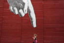 A woman runs past artwork of a large hand on a wall in central London, Britain April 27, 2015. REUTERS/Stefan Wermuth - LR2EB4R164ITN