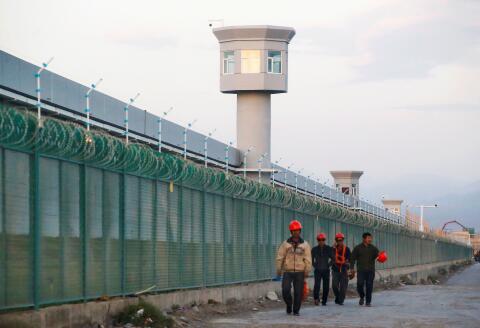 FILE PHOTO: Workers walk by the perimeter fence of what is officially known as a vocational skills education centre in Dabancheng in Xinjiang Uighur Autonomous Region, China September 4, 2018. REUTERS/Thomas Peter/File Photo