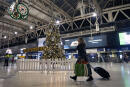 A woman pulls a suitcase past the Christmas tree on the concourse of Waterloo Station in central London, Sunday, Dec. 20, 2020. Millions of people in England have learned they must cancel their Christmas get-togethers and holiday shopping trips. British Prime Minister Boris Johnson said Saturday that holiday gatherings can‚Äôt go ahead and non-essential shops must close in London and much of southern England. (Victoria Jones/PA via AP)