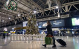A woman pulls a suitcase past the Christmas tree on the concourse of Waterloo Station in central London, Sunday, Dec. 20, 2020. Millions of people in England have learned they must cancel their Christmas get-togethers and holiday shopping trips. British Prime Minister Boris Johnson said Saturday that holiday gatherings can‚Äôt go ahead and non-essential shops must close in London and much of southern England. (Victoria Jones/PA via AP)