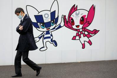 A man wearing a protective face mask walks in front of a wall decoration featuring Tokyo 2020 Olympic Games mascot Miraitowa and Paralympic mascot Someity, amid the coronavirus disease (COVID-19) outbreak in Tokyo, Japan December 24, 2020. REUTERS/Issei Kato