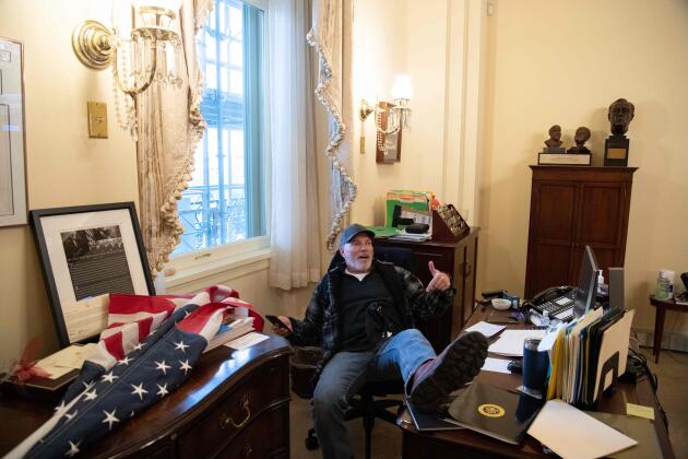 Un partisan de Donald Trump, les pieds sur le bureau de la speaker, Nancy Pelosi. Lors de cette intrusion, son bureau a été saccagé.