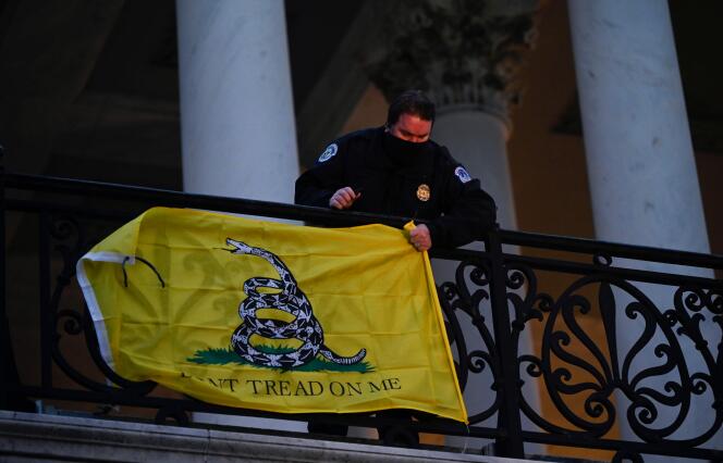 Un policier retire le drapeau de Gadsden, le 6 janvier, au Capitole.