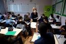 A teacher with a protective mask distributes documents to pupils in a classroom in Brequigny high school in Rennes, western France, on September 1, 2020 on the first day of the school year amid the Covid-19 epidemic. - French pupils go back to school on September 1 as schools across Europe open their doors to greet returning pupils this month, nearly six months after the coronavirus outbreak forced them to close and despite rising infection rates across the continent. (Photo by Damien Meyer / AFP)