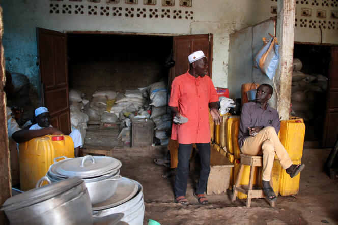 Adoum Adam (en rouge), responsable du transport et de logistique d’une entreprise de grossistes, devant un de ses entrepôts presque vide, à Bangui.