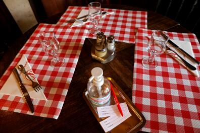A photograph taken on October 14, 2020 shows clients-registration tickets and a hand sanitizing gel bottle on a table in a restaurant in Paris, as new measures are expected to fight the rapid spread of Covid-19. - Restaurants have to respect new safety measures including providing sanitising hand gel, limiting patrons to six a table with at least a meter between seats, and allowing diners to remove their masks only for eating. (Photo by THOMAS COEX / AFP)
