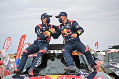 French driver Stephane Peterhansel (R) celebrates with teammates following his victory in the Dakar Rally in Saudi Arabia, on January 15, 2021. / AFP / FRANCK FIFE 