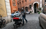 A woman wearing a face mask pushes a baby stroller in central Rome on April 15, 2020, during the country's lockdown aimed at curbing the spread of the COVID-19 pandemic, caused by the novel coronavirus. (Photo by Andreas SOLARO / AFP)