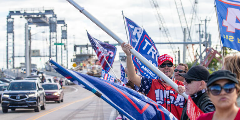 Supporters of former U.S. President Donald Trump rally while waving flags along Southern Boulevard in Palm Beach, Florida, as they wait for Trump's motorcade to pass by on his way to Mar-a-Lago, Wednesday, January 20, 2021.