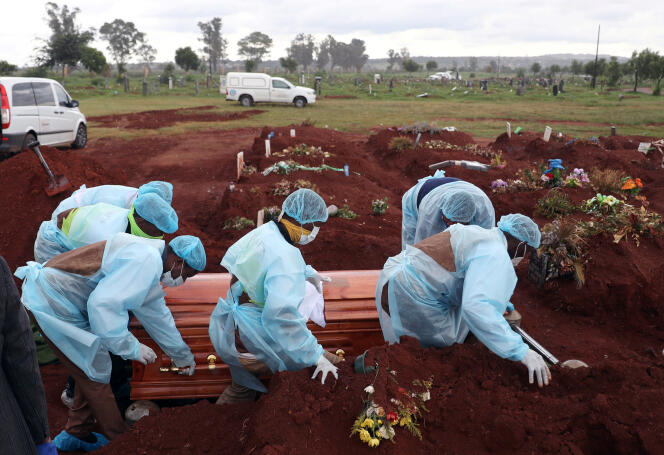 Des agents de santé sud-africains transportent le cercueil d’une victime du Covid-19 au cimetière d’Olifantsvlei, au sud-ouest de Johannesburg, le 6 janvier 2021.
