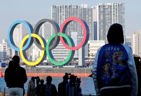 FILE PHOTO: Bystanders watch as giant Olympic rings are reinstalled at the waterfront area at Odaiba Marine Park, after they were temporarily taken down in August for maintenance amid the coronavirus disease (COVID-19) outbreak, in Tokyo, Japan December 1, 2020. REUTERS/Kim Kyung-Hoon/File Photo