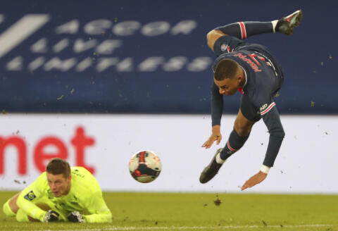 PSG's Kylian Mbappe, right, jumps over Montpellier's goalkeeper Jonas Omlin during the French League One soccer match between Paris Saint-Germain and Montpellier at the Parc des Princes stadium in Paris, France, Friday, Jan.22, 2021. (AP Photo/Thibault Camus)