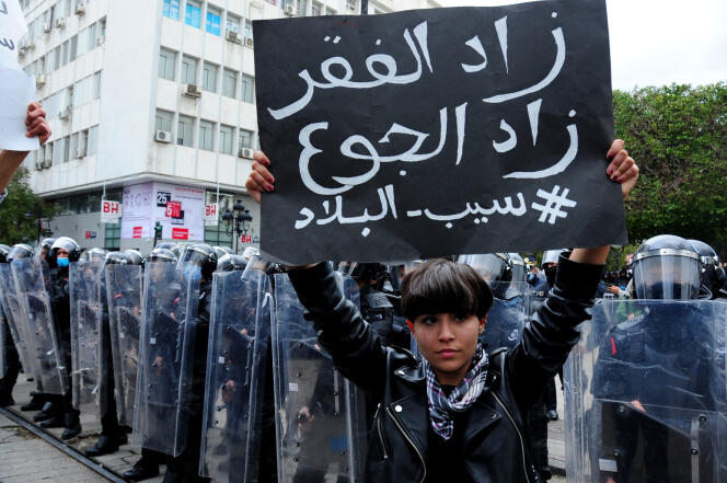 Une manifestante tient une affiche, sur laquelle est écrit « la pauvreté augmente, les privations augmentent », le 23 janvier à Tunis.