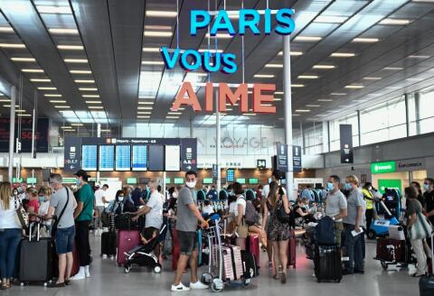 Travelers, wearing protective face masks, line up at the Orly Airport, south of Paris on August 1, 2020 during a major weekend of the French summer holidays. (Photo by STEPHANE DE SAKUTIN / AFP)