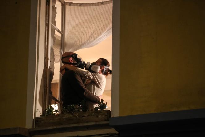 A couple wearing gas and filter masks kiss each other during applause in Nice in March 2020.