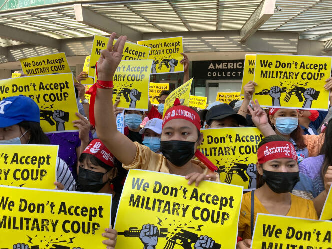 Des manifestants birmans rassemblés devant le centre commercial de Hledan, à Rangoun, font le signe des trois doigts, tout en brandissant des pancartes sur lesquelles l’on peut lire « Nous n’acceptons pas le coup d’état militaire », le 13 février 2021.
