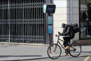 FILE - In this March 19, 2020 file photo, a food delivery service man rides his bike in Paris. Some 19 meal delivery companies in France including Uber Eats and Deliveroo have pledged to the French government to reduce their operational waste. With the pandemic-forced closure of restaurants, there has been a boom in home food delivery -- generating more waste that ever before. (AP Photo/Michel Euler, File)