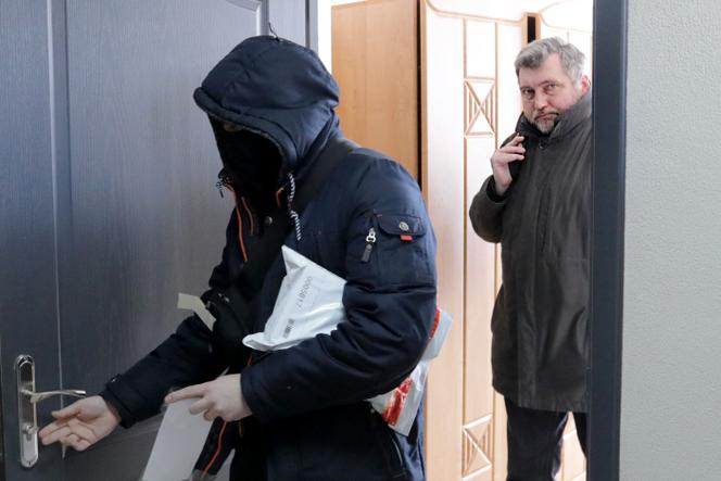 Le président de l’Association bélarussienne des journalistes (BAJ) Andreï Bastunets et des policiers biélorusses quittent le bureau de la BAJ après une descente à Minsk, le 16 février 2021.