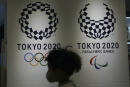 A child wearing a protective mask to help curb the spread of the coronavirus runs in front of the logos of the Tokyo 2020 Olympic and Paralympic Games Tuesday, Feb. 23, 2021, in Tokyo. Japan began to roll out coronavirus vaccines on Wednesday, a critical move that might boost the Olympics. (AP Photo/Eugene Hoshiko)