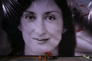 FILE - In this Tuesday, Oct. 16, 2018 file photo, flowers and a candle lie in front of a portrait of slain investigative journalist Daphne Caruana Galizia during a vigil outside the law courts in Valletta, Malta. One of three men accused of killing Maltese investigative journalist Daphne Caruana Galizia in a 2017 car bombing changed his plea to guilty during a hearing Tuesday and was immediately sentenced to 15 years in prison. The man, Vince Muscat, together with Alfred and George Degiorgio, had been accused of detonating the bomb that killed Caruana Galizia as she was driving her car Oct. 16, 2017. (AP Photo/Jonathan Borg, File)