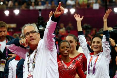 (FILES) In this file photo taken on July 31, 2012, US women gymnastics team's coach John Geddert celebrates with the rest of the team after the US won gold in the women's team artistic gymnastics event at the London Olympic Games. Geddert has been charged with human trafficking and criminal sexual conduct, prosecutors said on February 25, 2021. Michigan Attorney General Dana Nessel unveiled a 24-count complaint against Geddert, who owned a training facility where convicted sex offender Larry Nassar served as the gym doctor. / AFP / - 