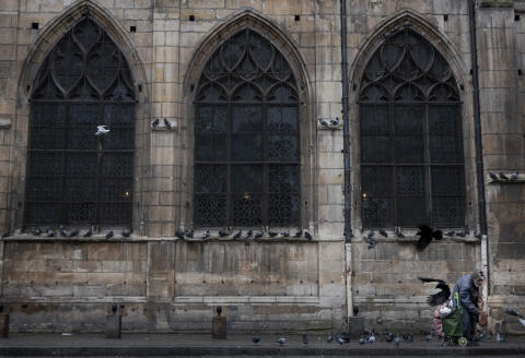 A homeless person feeds pigeons and other birds in front of the Catholich church of Saint Merry in Paris, France on November 10 ,2019. (Photo by JOE KLAMAR / AFP)