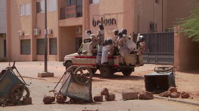 Des policiers anti-émeute se dirigent vers un groupe de manifestants à un poste de contrôle de fortune, à Niamey, le 24 février 2021.