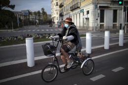 Nice resident Noel and her dog Glugi go for a bike ride during confinement in Nice, southern France, Saturday, Feb. 27, 2021. Nice and the surrounding coastal area will be under weekend lockdowns for at least two weeks, in addition to a national 6 p.m. to 6 a.m. curfew, imposed to curb soaring COVID-19 infections. (AP Photo/Daniel Cole)