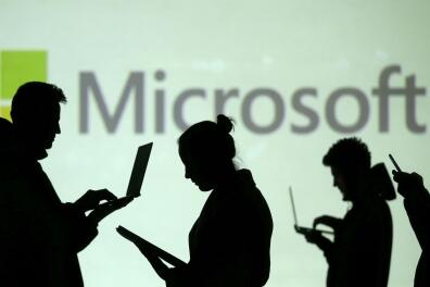 FILE PHOTO: Silhouettes of laptop and mobile device users are seen next to a screen projection of Microsoft logo in this picture illustration taken March 28, 2018. REUTERS/Dado Ruvic/Illustration/File Photo