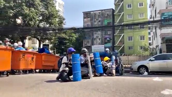 Des manifestants se protègent derrière des poubelles, jeudi 4 mars, à Rangoun, en Birmanie.