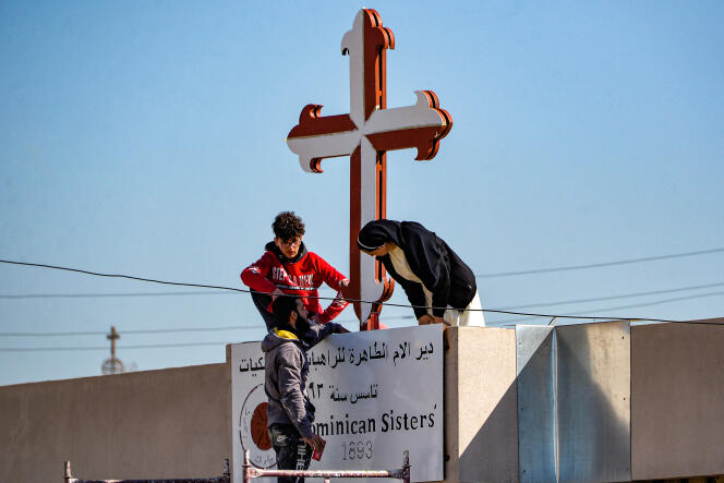 Une religieuse chrétienne repeint le crucifix à l’entrée d’un couvent à Karakoch, en prévision de la visite du pape François, en Irak, février 2021.