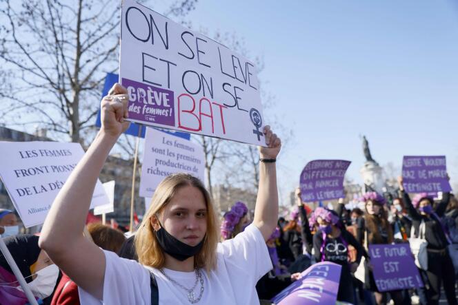 Une manifestante porte une pancarte sur laquelle figure l’inscription « On se lève et on se bat », lors d’un rassemblement à Paris, dimanche, à la veille de la Journée internationale des droits des femmes.