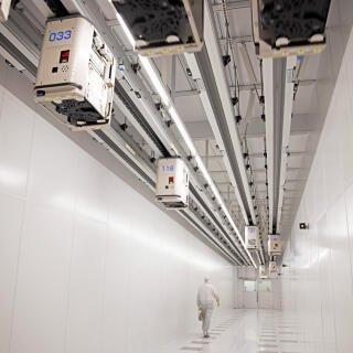 An employee passes beneath automated transport system cars carrying silicon wafer boxes in the clean rooms at the Globalfoundries semiconductor fabrication (fab) plant in Dresden, Germany, on Thursday, Feb. 11, 2021. The EU outlined a goal last year to produce at least one-fifth of the worlds chips and microprocessors by value, without giving details on how this would be achieved. Photographer: Liesa Johannssen-Koppitz/Bloomberg via Getty Images