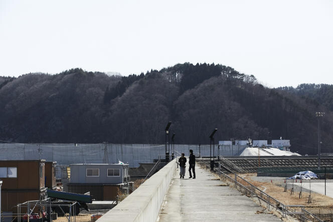 Deux personnes marchent sur l’ancienne digue de Taro (en arrière-plan, la nouvelle digue). Taro, le 28 février 2021.
