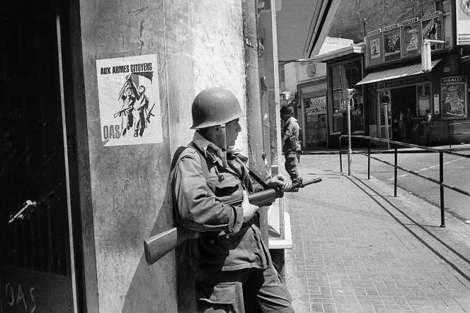 Un soldat français, devant une affiche de l’OAS, appelant à prendre les armes contre l’indépendance algérienne, à Oran (Algérie), le 15 mai 1962.